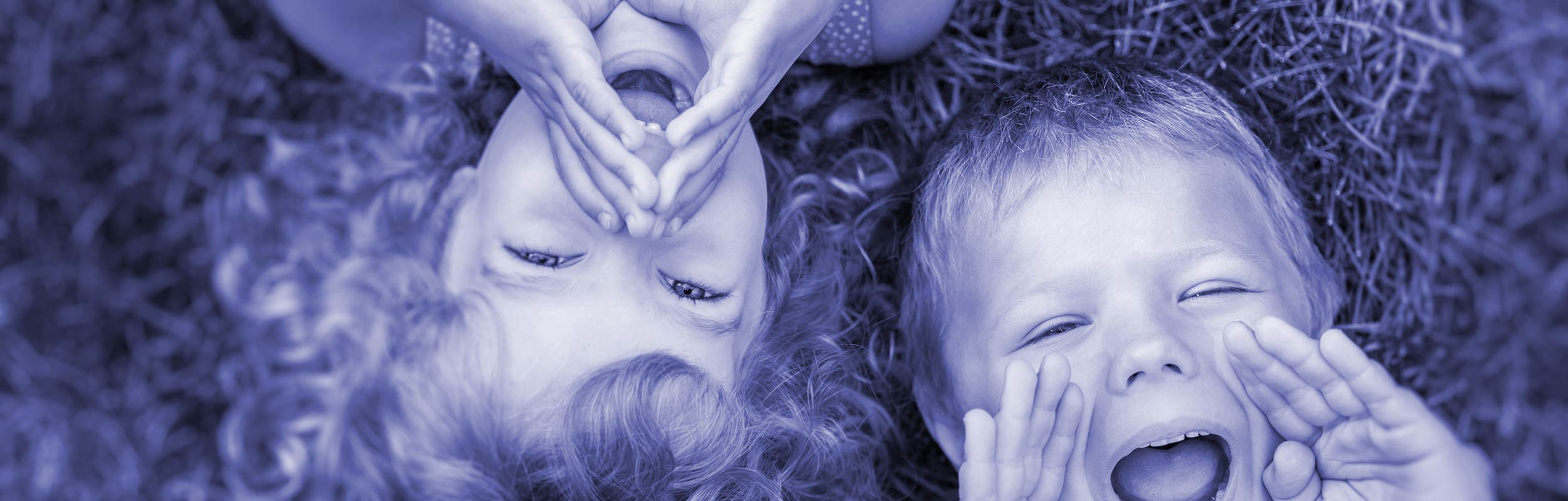 looking down a boy and girl lying on grass taking to the camera